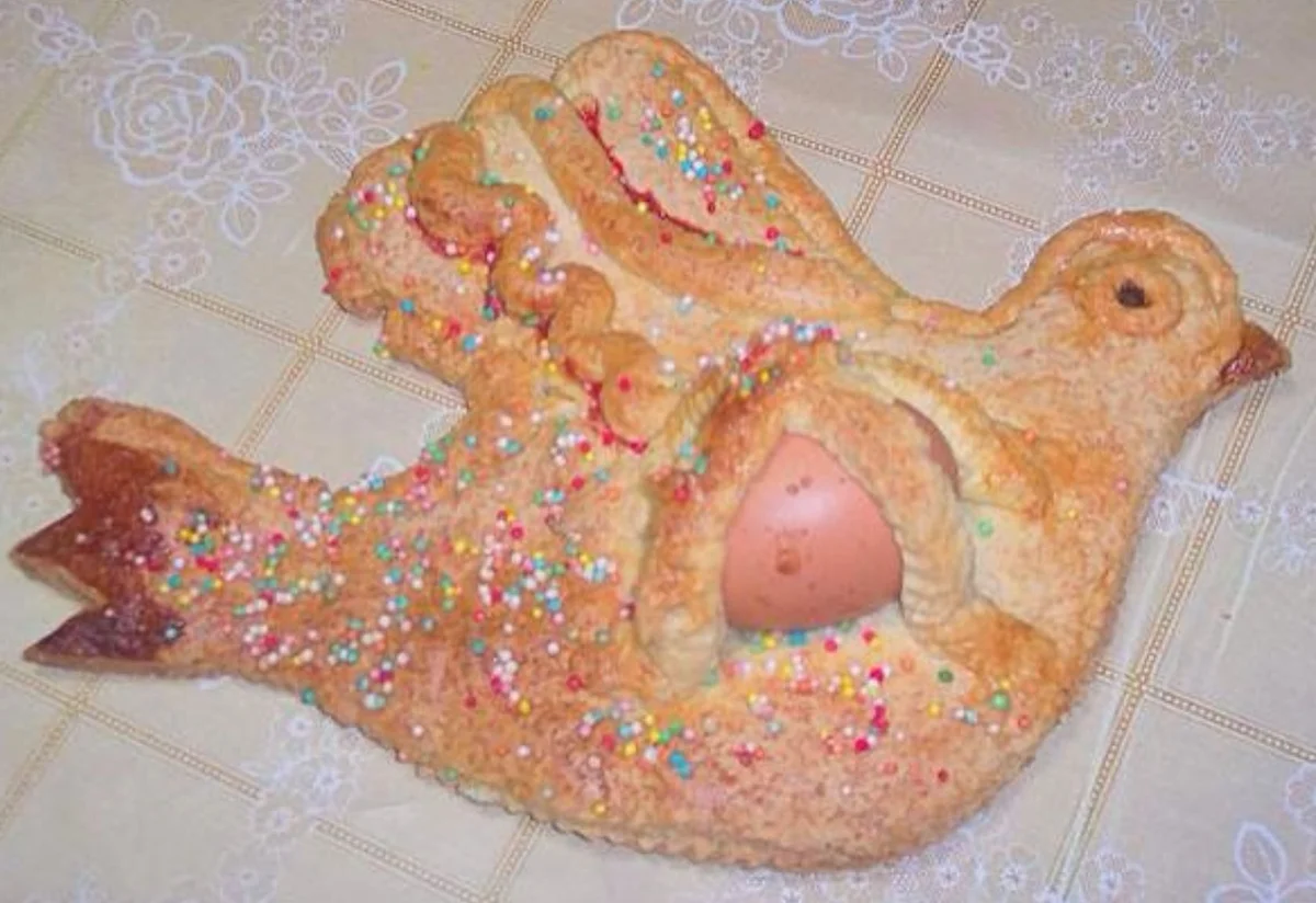 Traditional Catanian Easter bun aceḍḍu cull’ovu decorated with sprinkles and a whole egg