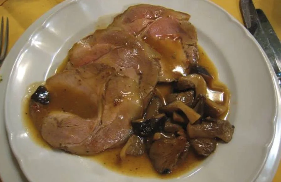 Arrosto di vitello ai funghi porcini servito con salsa cremosa e funghi su piatto di ceramica siciliana