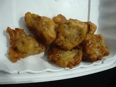 Carciofi in pastella dorati serviti con fette di limone su piatto rustico siciliano