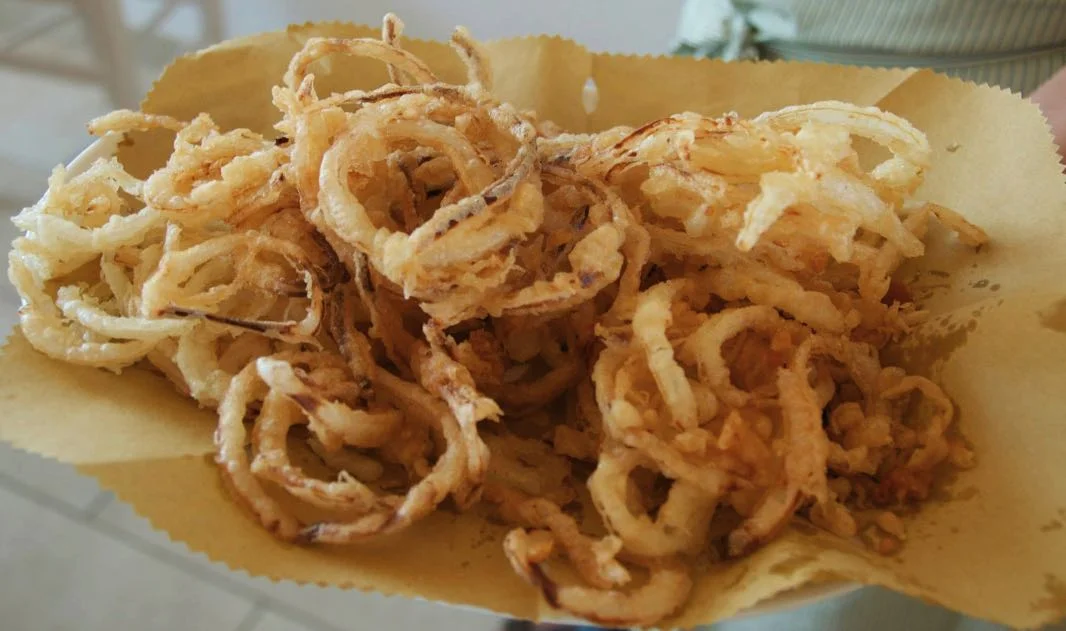 Anelli di cipolle fritte dorati serviti su piatto in ceramica siciliana