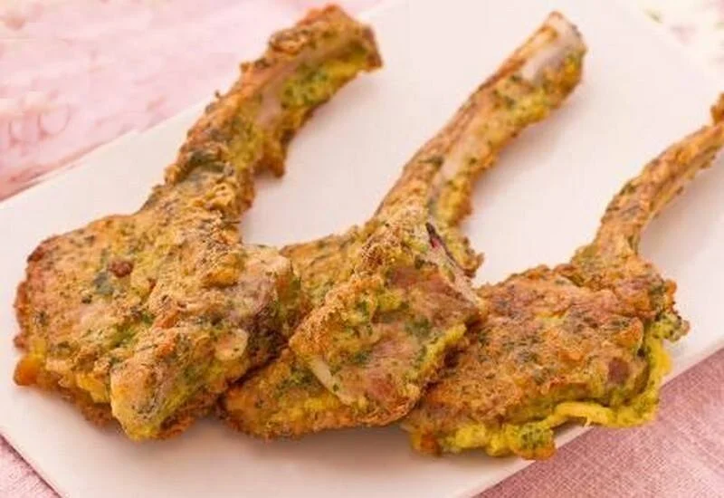 Golden breaded lamb cutlets with thyme on a serving tray with lemon slices