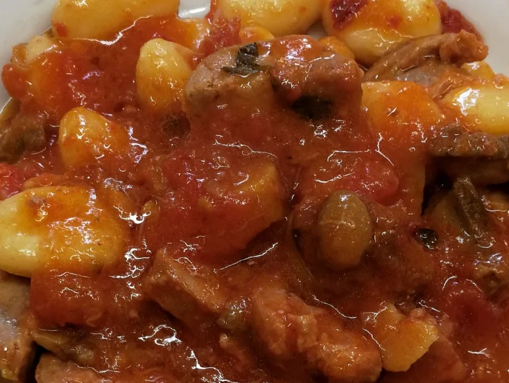 Gnocchi con funghi porcini e salsiccia serviti su piatto di ceramica siciliana