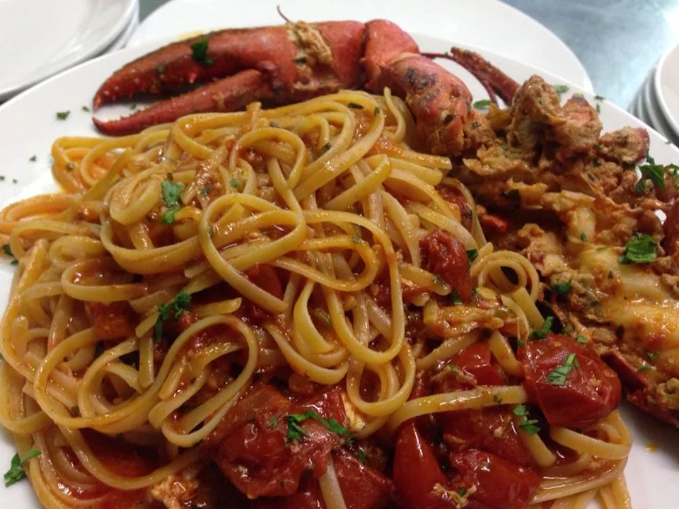 Linguine all’astice servite su piatto siciliano decorato con prezzemolo e pomodorini