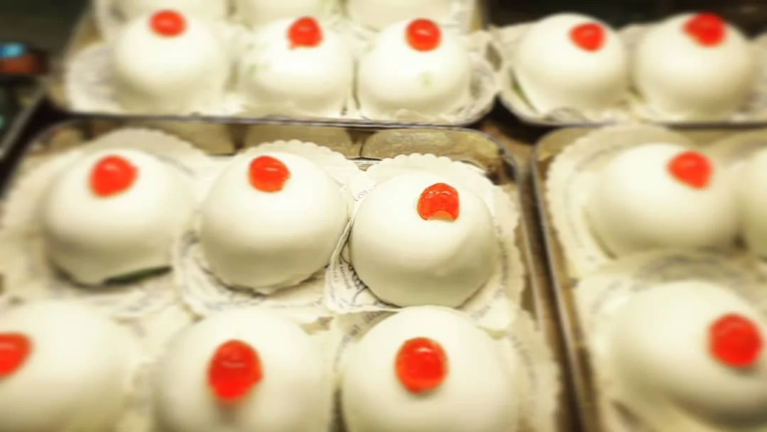 Minne di Sant’Agata coperte di glassa bianca e decorate con ciliegie candite su piatto siciliano