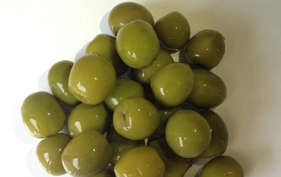olive verdi in salamoia immerse in barattoli di vetro con foglie di alloro e spicchi d’aglio
