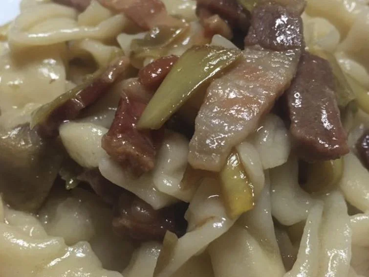 Pasta con carciofi e pancetta servita su piatto di ceramica siciliana