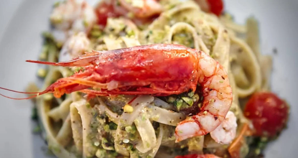 Pasta con gamberi e pistacchio di Bronte servita in piatto ceramico siciliano