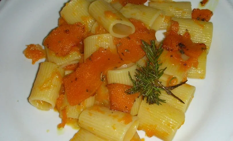 Pasta con la zucca servita in piatto rustico con pancetta croccante e pepe nero