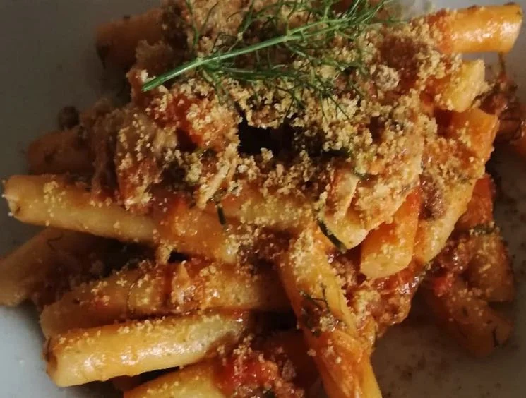 Pasta con sgombro e finocchietto servita in piatto di ceramica siciliana decorata