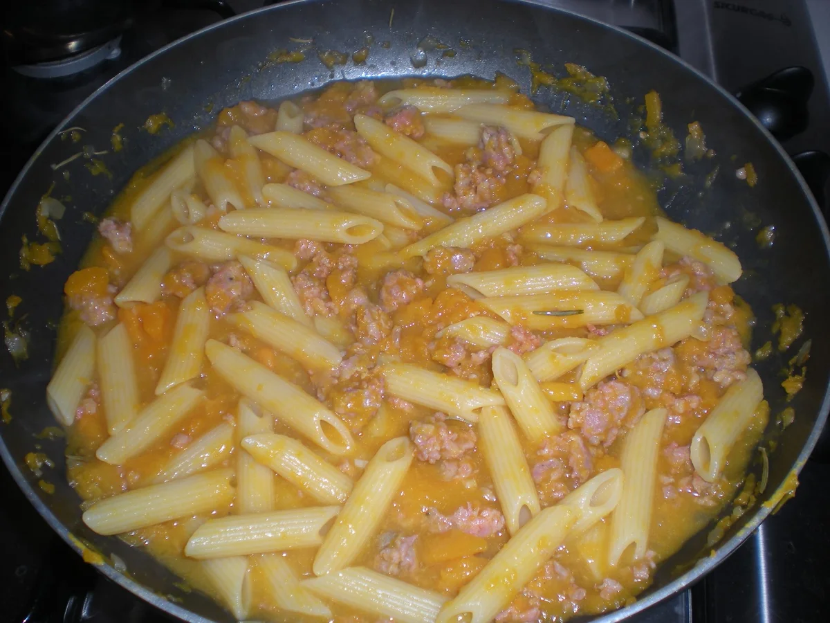 Pasta con zucca e salsiccia servita in piatto siciliano decorato