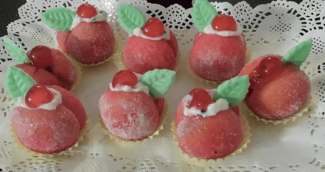 Pesche dolci siciliane ripiene di ricotta e decorate con alchermes e zucchero