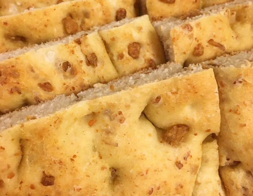 Scacciata chî frittuli dorata e fragrante, appena sfornata, con ciccioli di maiale visibili nell’impasto