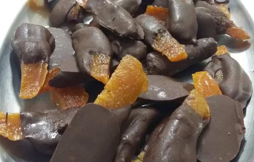 Scorze di arancia candite immerse nel cioccolato fondente su piatto di ceramica siciliana