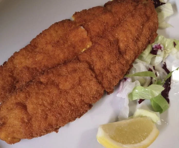 Sgombri a cotoletta dorati serviti su piatto in ceramica siciliana con limone e prezzemolo