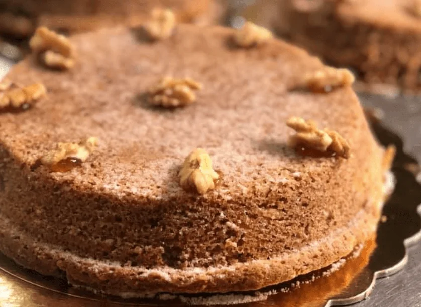 Torta alle noci siciliana con cioccolato fondente e zucchero a velo su piatto di ceramica messinese