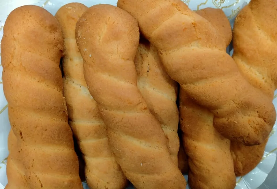 Treccine siciliane dorate su tavola in legno con tazza di latte